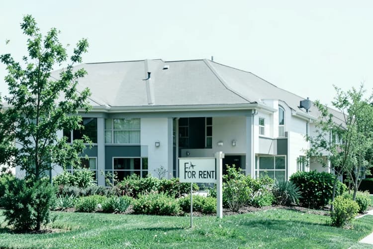 Fachada de uma casa residencial bem cuidada com jardim e placa de "Aluga-se"