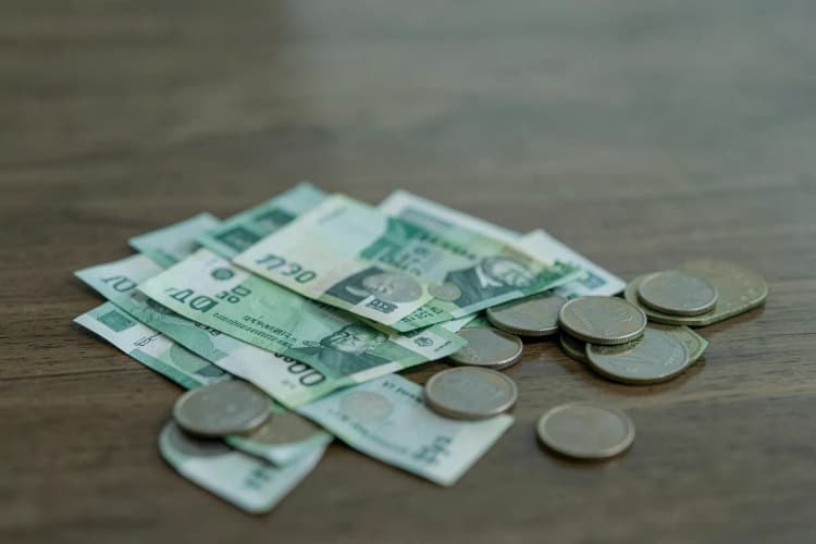Close-up de notas de dinheiro e moedas sobre uma mesa, simbolizando o cálculo de preço.