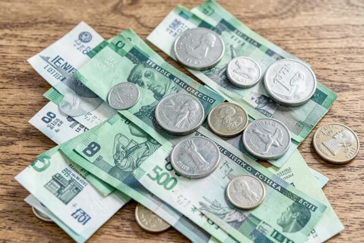 Close-up de notas de dinheiro e moedas sobre uma mesa, simbolizando custos de aluguel