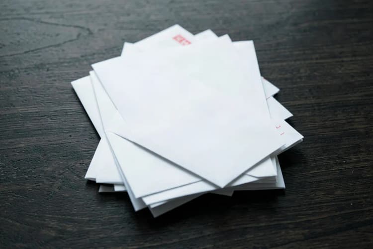 Uma pilha de contas e boletos em cima de uma mesa de madeira escura.